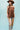 A woman  a brown lace camisole top, light blue patchwork jeans with floral patches, an olive baseball cap, and brown strappy heelsFleaStyle