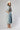 A woman wearing a bohemian-style Crochet-Duster-Cardigan-Ivory_Blue-FleaStyle, a brown  top, wide-leg denim jeans, an ivory white cowboy hat, and lace-up heeled sandals-FleaStyle