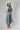 A woman wearing a bohemian-style Crochet-Duster-Cardigan-Ivory_Blue-FleaStyle, a brown  top, wide-leg denim jeans, an ivory white cowboy hat, and lace-up heeled sandals-FleaStyle