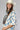 A woman wearing a bohemian-style Crochet-Duster-Cardigan-Ivory_Blue-FleaStyle, a brown  top, wide-leg denim jeans, an ivory white cowboy hat, and lace-up heeled sandals-FleaStyle