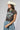 A woman wearing a brown graphic t-shirt with an eagle design and 'Free Bird' text, paired with an ivory cowboy hat and  Button Down Pleated Cropped Denim Pants-FleaStyle