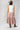 A woman wearing a brown straw cowboy hat, white sleeveless top, and a Tiered Asymmetrical Ruffle Plaid Midi Skirt - Red/Orange-FleaStyle