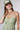 A woman wearing a light sage green strapless midi dress with a gathered sweetheart neckline, paired with brown cowboy boots, an olive  trucker hat, and a gold necklace-FleaStyle