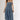 A woman wearing a strapless tiered denim maxi dress in a medium blue wash, paired with a brown baseball cap that reads 'Laguna BEACH' and layered gold necklaces-Fleastyle