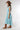 A woman wearing a brown straw cowboy hat, a light blue sleeveless crop top, and a matching pleated skirt, accessorized with a chunky gold necklace-Balloon Crop Top - Blue-FleaStyle