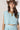 A woman wearing a brown straw cowboy hat, a light blue sleeveless crop top, and a matching pleated skirt, accessorized with a chunky gold necklace-Balloon Crop Top - Blue-FleaStyle
