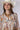 A woman wearing an ivory cowboy hat and a long-sleeve, balloon-silhouette blouse with a colorful paisley and floral print, paired with dark denim shorts-Button Down Paisley Printed Blouse - Pink/Orange