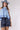 A woman wearing a light blue sleeveless ruffled top, dark blue paisley patterned denim shorts,a dusty blue cowboy hat-Halter Neck Sleeveless Tie Ruffle Top - Light Blue