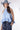 A woman wearing a light blue sleeveless ruffled top, dark blue paisley patterned denim shorts,a dusty blue cowboy hat-Halter Neck Sleeveless Tie Ruffle Top - Light Blue