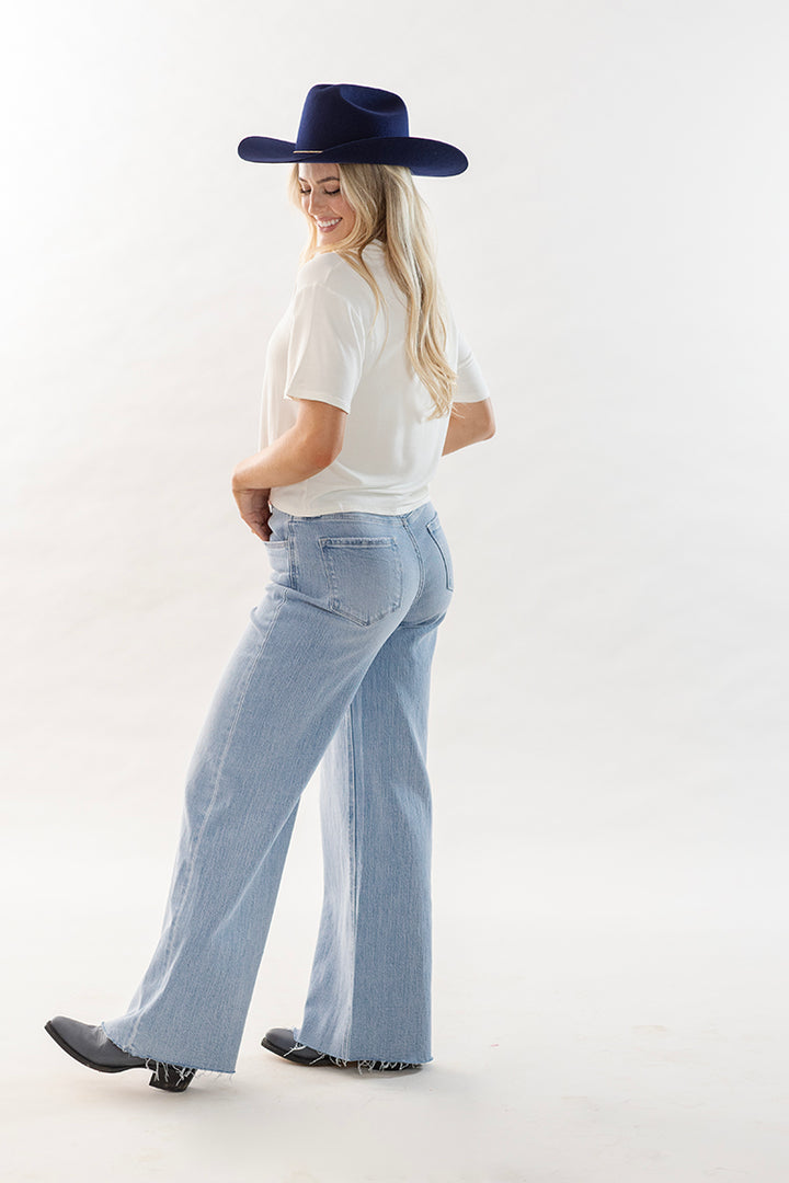 Woman wearing a cowboy graphic t-shirt, light blue wide leg jeans and boots with a navy cowboy hat-Flea Style