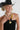 A woman wearing a black straw cowboy hat and black strapless dress with avintage beaded necklace featuring mustard marbled beads, large black cylindrical beads, pops of red and turquoise accents, antiqued silver-tone spacer beads, and an oversized cream mosaic tile pendant -Vintage_Mixed_Bead_Mosaic_Pendant_Necklace-FleaStyle