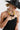 A woman wearing a black straw cowboy hat and black strapless dress with avintage beaded necklace featuring mustard marbled beads, large black cylindrical beads, pops of red and turquoise accents, antiqued silver-tone spacer beads, and an oversized cream mosaic tile pendant -Vintage_Mixed_Bead_Mosaic_Pendant_Necklace-FleaStyle