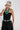 A woman wearing a beige trucker-style cap with a colorful butterfly patch, a black strapless dress,avintage turquoise-hued geometric beads with dark marbled detailing and small metal accents-Vintage_Turquoise_Geometric_Statement_Necklace-FleaStyle