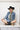 Woman wearing a denim jacket, cowboy hat, and Upcycled-Vintage-Tie-Necklace-DarkGreen with a gold chain and one-of-a-kind vintage gold brooch-Fleastyle