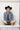 Woman wearing a denim jacket, black cowboy hat, and Upcycled Vintage Tie Necklace - Brown Rhinestone with a vintage brooch with gold leaf accent-Fleastyle