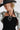 A woman wearing a black straw hat, a black ribbed strapless dress, a silver sage bandana scarf and a silver heart-shaped pendant necklace with a strand of black and clear faceted beads-Vintage Black Beaded Heart Pendant Necklace- FleaStyle
