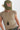 A woman wearing an olive green trucker hat with an embroidered butterfly patch on the front, paired with a beige short-sleeve top and a long pendant necklace-Butterfly_Patch_Trucker_Hat_-_Olive-FleaStyle