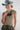 A woman wearing a toasted dusty blue cowboy hat, a beige short-sleeve t-shirt, and camouflage pants, accessorized with a vintage necklace with a mix of carved dark-tone wood beads in organic shapes, and layered hanging accents with rich texture-Vintage_Carved_Wood_Statement_Necklace-FleaStyle