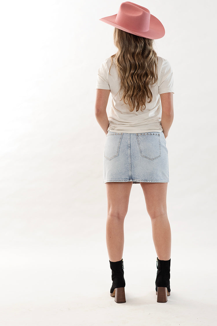 Women wearing a white Dolly Parton graphic t-shirt, denim skirt, and a pink cowboy hat -Flea Style