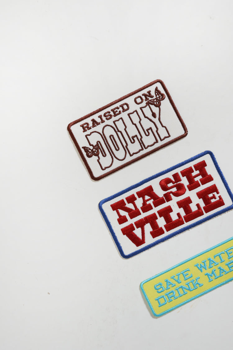 Embroidered patches with "Raised on Dolly" text with butterfly embellishments. 