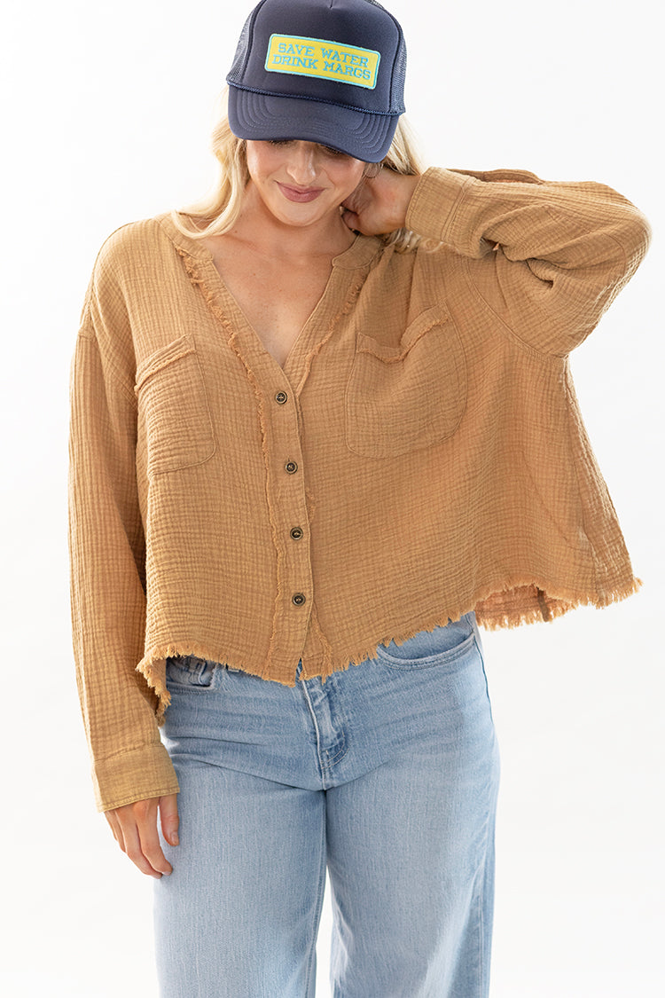 Woman wearing a tan button-up gauze shirt, light blue jeans, and a navy trucker cap-Flea Style