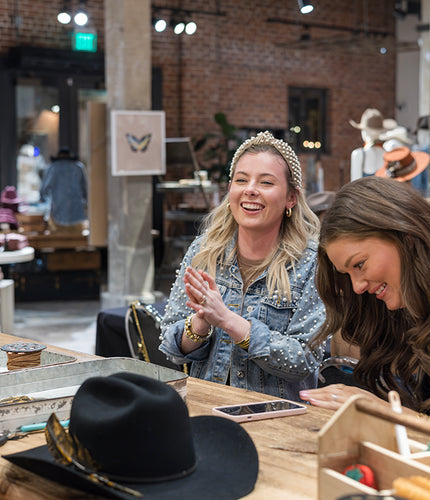 Women shopping and customizing hats at the Original Hat Bar with friends and stylists, showcasing the custom hat design experience and linking to book a reservation