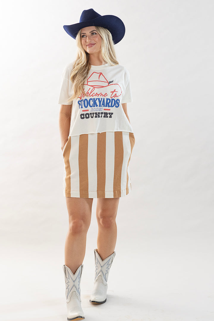 Woman wearing a white cropped graphic t-shirt with vintage rodeo lettering, stripe dress and a blue cowboy hat-Flea Style