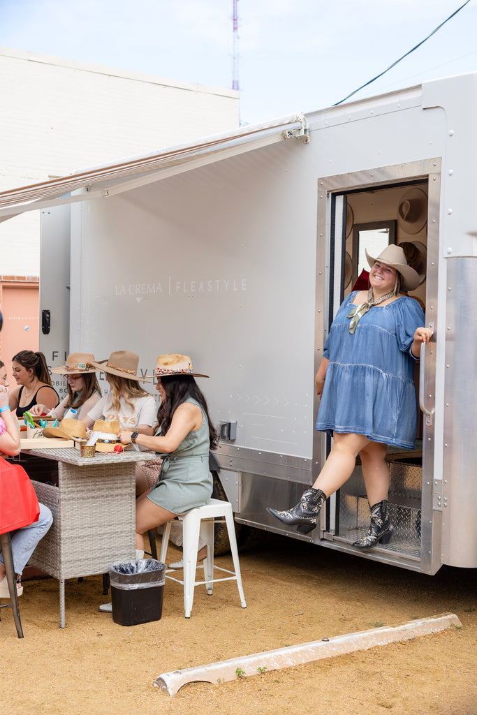 Smiling woman wearing a cowboy hat walking out of the mobile truck