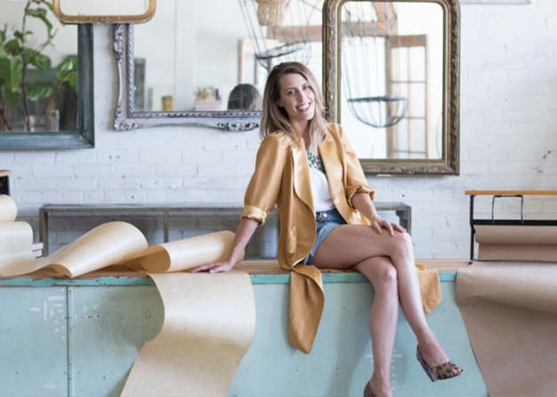 Woman sitting on a counter in front of a collage of mirrors 