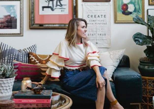 Woman sitting on a couch with artwork around her